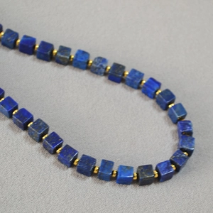Vintage lapis lazuli square bead necklace with gold spacer beads on grey textured cloth