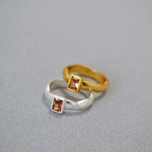 Macro detail of hammered texture rings with amber square zircons in gold and silver finish