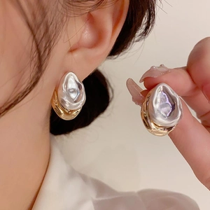 Close-up of irregular liquid metal earrings with mixed gold and silver melting textures