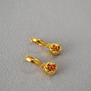 Macro view of gold plated pomegranate earrings featuring sparkling red zircon crystals