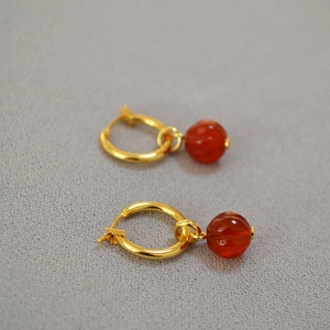 Detailed macro of red agate lantern charm earrings with gold hoop in a festive style