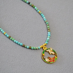 Gros plan détaillé d'un collier de perles fait main avec pendentif fleur et papillon émaillé