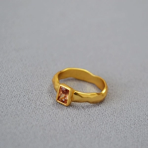 Detail of hammered gold ring featuring a rectangular amber zircon stone in macro view