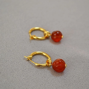 Close-up of gold hoop earrings featuring red agate pumpkin lanterns in neo-Chinese style