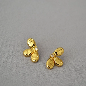 Détail de boucles d'oreilles fleurs dorées vintage avec petits zircons centraux