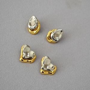 Detail view of modern asymmetric water drop and heart earrings with silver and gold plating