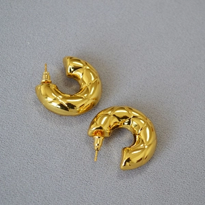 Detailed view of hollow gold-plated brass C-shaped hoop earrings with quilted texture