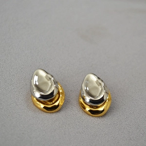 Detail of irregular liquid-style melted heart earrings in gold and silver finish