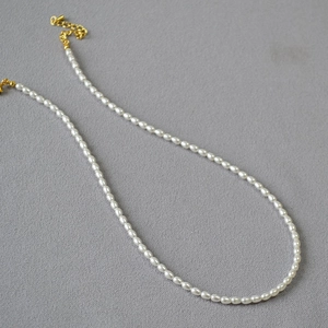 Élégant collier de perles blanches avec fermoir doré et chaîne réglable sur fond gris