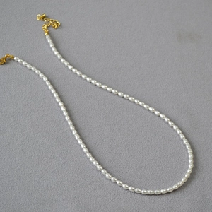 Détail d'un collier de perles blanches avec fermoir mousqueton doré et chaîne d'extension