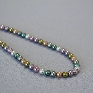 Close-up of multicolor 6-8mm round pearls with rich luster on textured fabric background