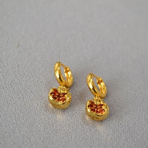 Detailed view of gold-plated apple earrings with red pavé crystals and hoop closure