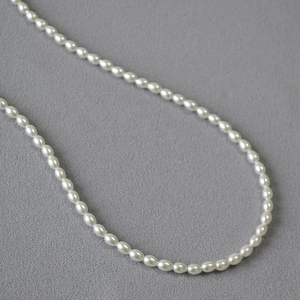 Vue détaillée du collier de perles ovales de 5 mm sur un fond sombre texturé