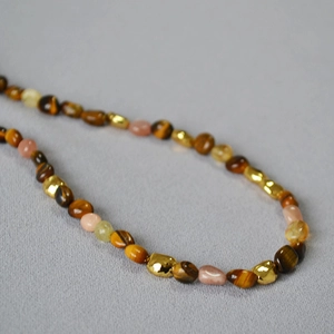 Macro view of tiger eye stones and irregular gold beads on a beaded necklace