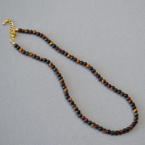 Detailed close-up of tiger eye beads necklace with gold lobster clasp and extension chain