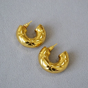 Macro detail of gold-plated brass hoop earrings with elegant quilted rhombus texture