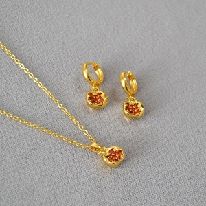 Detailed shot of brass gold-plated pomegranate pendant necklace and hoop earrings set