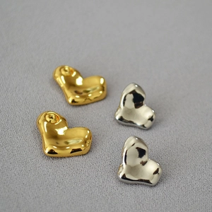 Detail view of irregular heart-shaped earrings in polished gold and silver finishes
