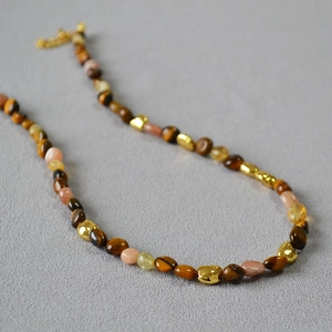 Macro shot of tiger eye beads and sunstone beads with golden metallic accents