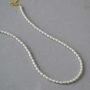 Détail macro d'un collier de perles de riz blanches avec fermoir et chaîne dorés
