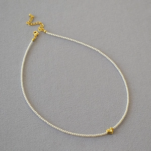 Detailed view of elegant pearl necklace with a gold heart pendant and lobster clasp