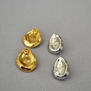 Macro shot of irregular lava-style earrings in gold and silver with mirror finish