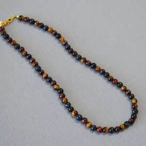 Detailed macro view of mixed tiger eye stone beads and golden clasp on short necklace