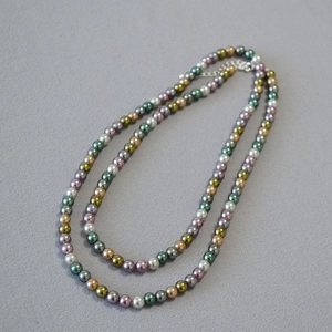 Detail of colorful beads necklace with pearl texture and metal clasp on grey fabric