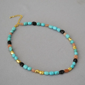 Detailed shot of bohemian beaded necklace featuring turquoise, pink beads and gold lobster clasp