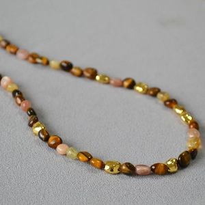 Vintage tiger eye stone beaded necklace with gold metal accents on gray textured fabric