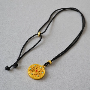 Macro detail of Chinese style gold-plated filigree disk pendant with turquoise and red beads