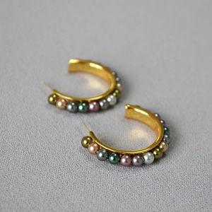 Close-up of C-shaped gold hoop earrings featuring multi-colored pearls and 925 silver needle