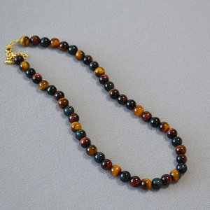Detail view of colorful tiger eye stone beads necklace with golden lobster clasp and chain
