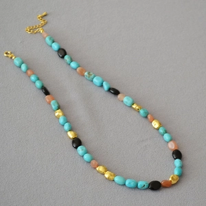 Detail of bohemian turquoise and multicolored irregular beaded necklace with golden clasp