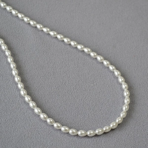 Vue détaillée de perles ovales blanches élégantes sur un tissu texturé gris de qualité
