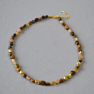 Detailed view of vintage tiger eye and peach stone beaded necklace with gold accents.