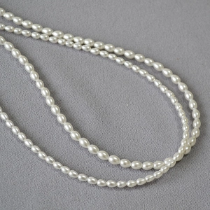 Vue macro de perles ovales blanches brillantes sur fond de tissu texturé gris foncé