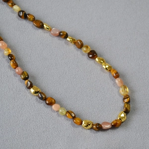 Detailed view of retro beaded necklace with tiger eye stones and golden metal spacers
