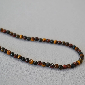 Retro mixed color tiger eye stone beaded necklace for women on a textured grey surface