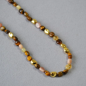 Close-up of tiger eye stones and pink quartz beads with irregular gold metal accents