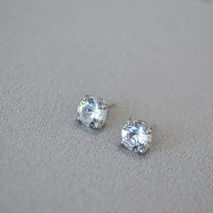 Macro shot of silver stud earrings with classic four-prong set round clear cubic zirconia