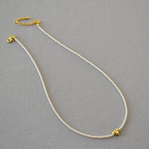 Elegant pearl necklace with a polished gold heart pendant in a minimalist U-shaped layout