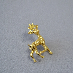 Eleganter Gold-Rentier-Anstecknadel mit poliertem Spiegel-Finish auf grauem Stoff