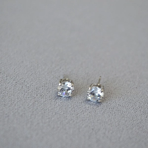 Detailed macro view of silver four-prong stud earrings with clear round cubic zirconia