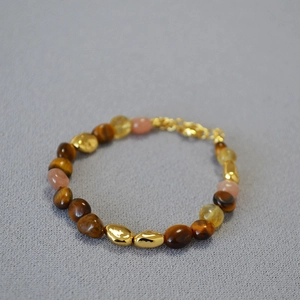 Detail of beaded necklace featuring tiger eye stones, sunstones and gold metal spacers