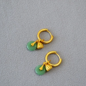 Détail de boucles d'oreilles dorées avec anneaux en jade vert et charms lotus délicats