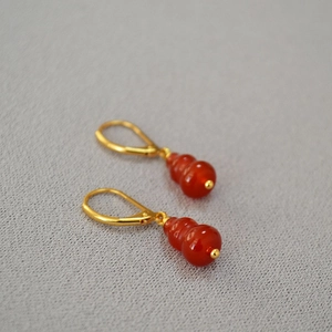 Macro detail of red agate gourd earrings with elegant gold hooks in traditional style