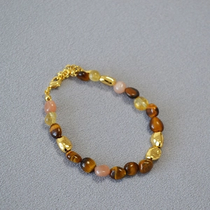Detail of beaded necklace with tiger eye, rose quartz and gold metal spacers
