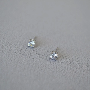 Detailed close-up of a silver four-prong stud earring with sparkling cubic zirconia