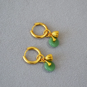 Détail de boucles d'oreilles lotus dorées avec jade vert et pendentif pingan chinois